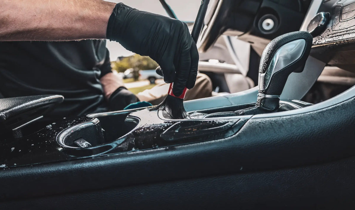 Sud Masters detailer cleaning a vehicle's interior console during mobile maintenance detailing
